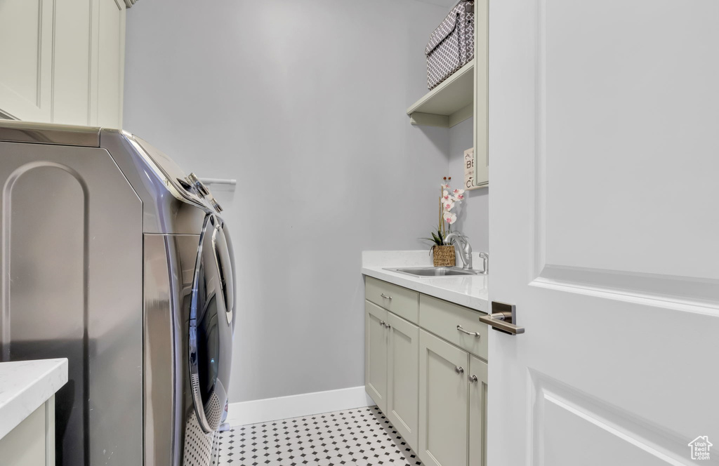 Laundry area with light tile flooring, cabinets, washer and clothes dryer, and sink