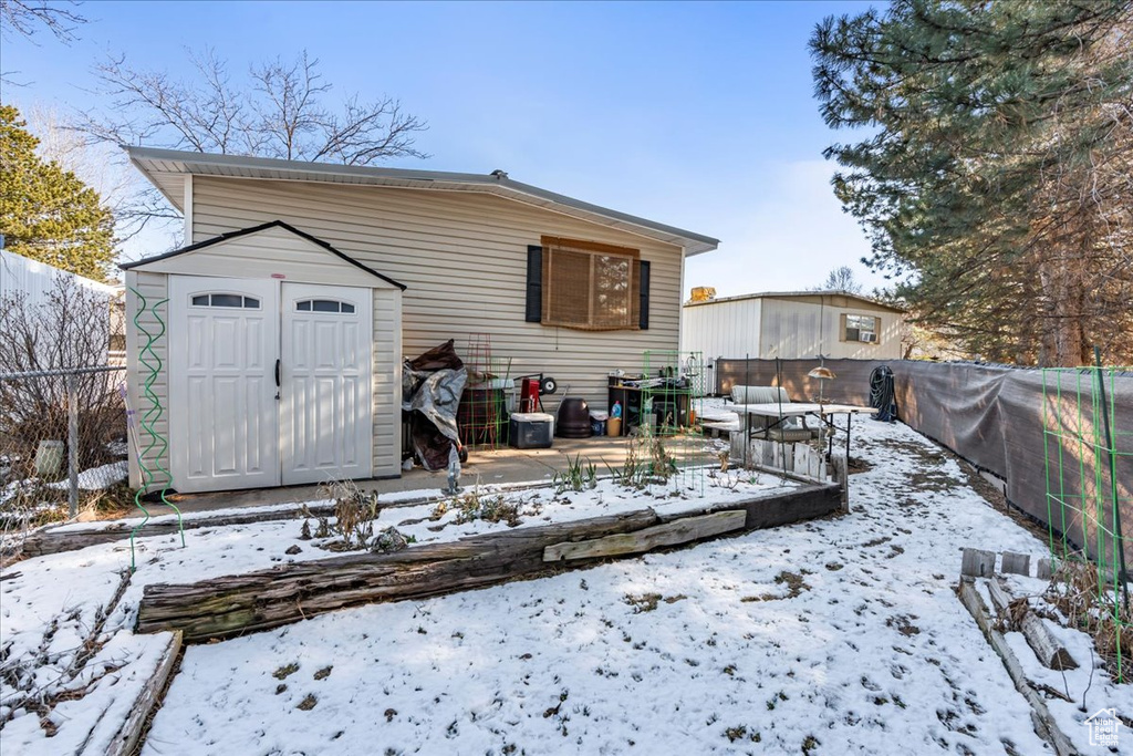 Snow covered property with a shed and a patio area