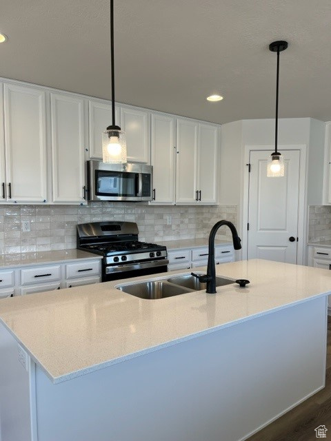 Kitchen featuring dark hardwood / wood-style floors, pendant lighting, appliances with stainless steel finishes, and white cabinets