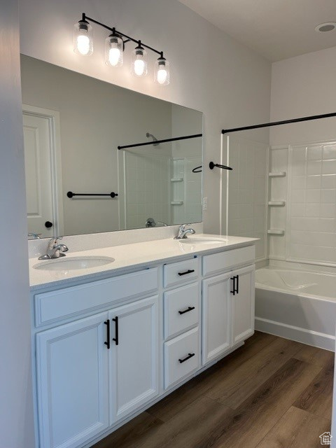 Bathroom featuring hardwood / wood-style floors, double sink vanity, and washtub / shower combination