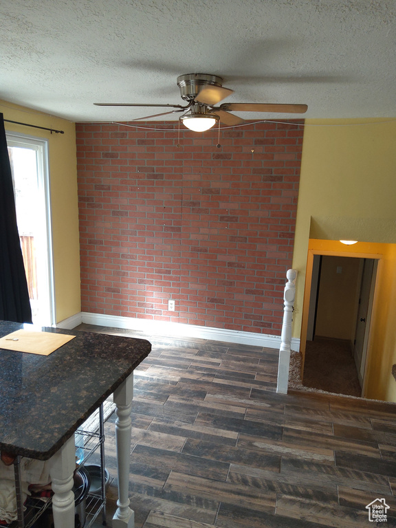 Interior space featuring brick wall, dark hardwood / wood-style floors, a textured ceiling, and ceiling fan