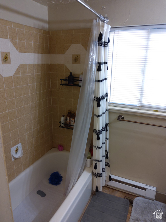 Bathroom featuring a baseboard heating unit and shower / tub combo
