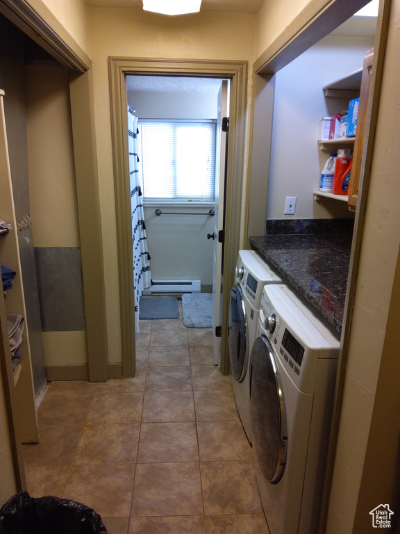 Laundry room featuring light tile floors, baseboard heating, and washing machine and clothes dryer