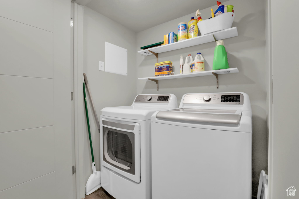 Washroom with hardwood / wood-style flooring and washer and dryer