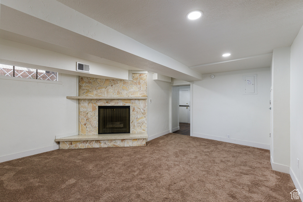 Basement featuring a fireplace, a textured ceiling, and dark colored carpet