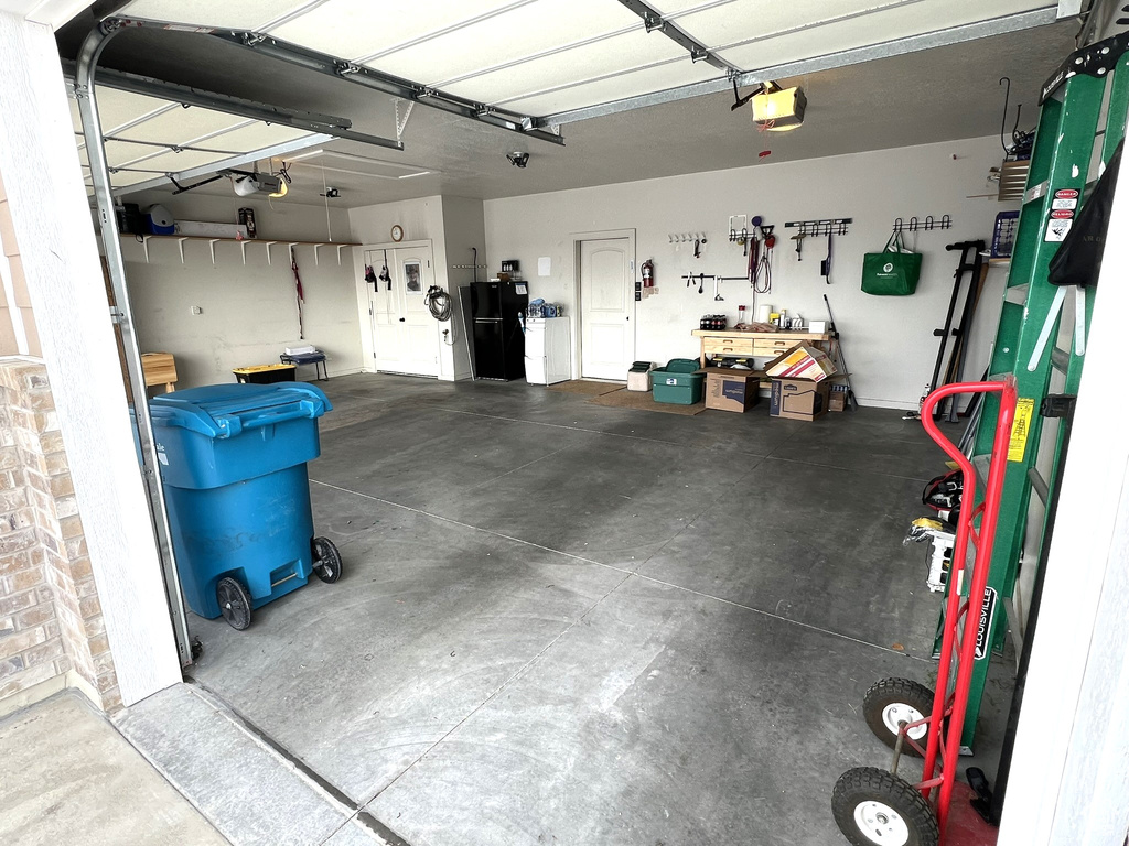 Garage featuring black fridge, a workshop area, and a garage door opener