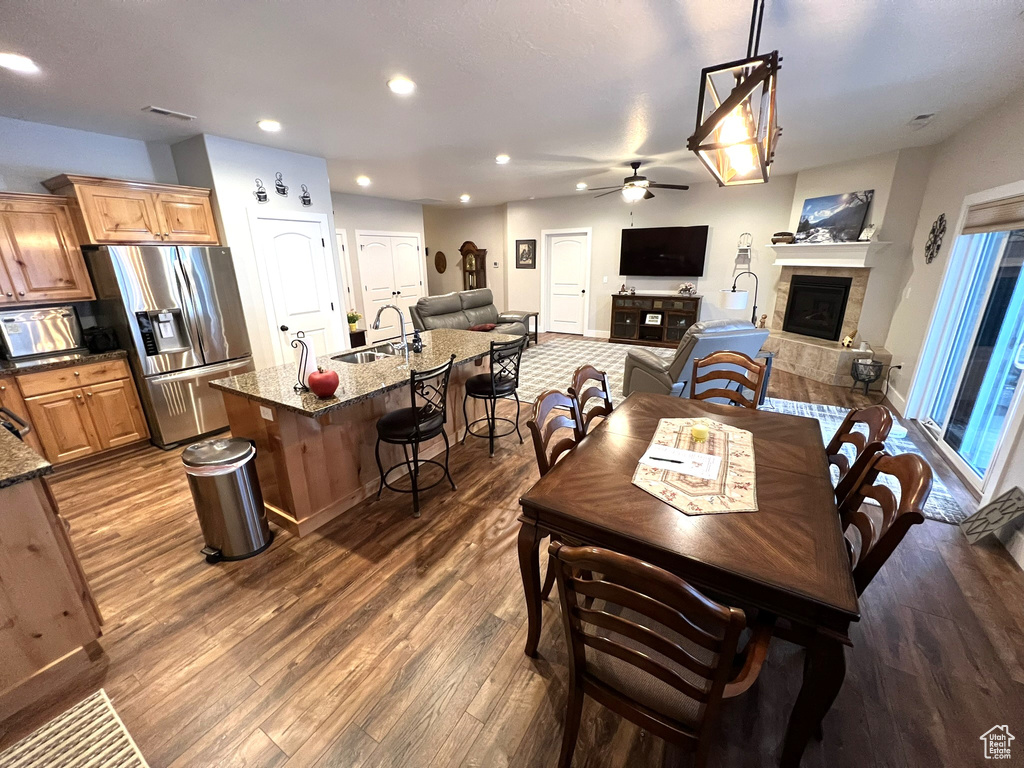 Dining space with dark hardwood / wood-style flooring, sink, ceiling fan, and a fireplace