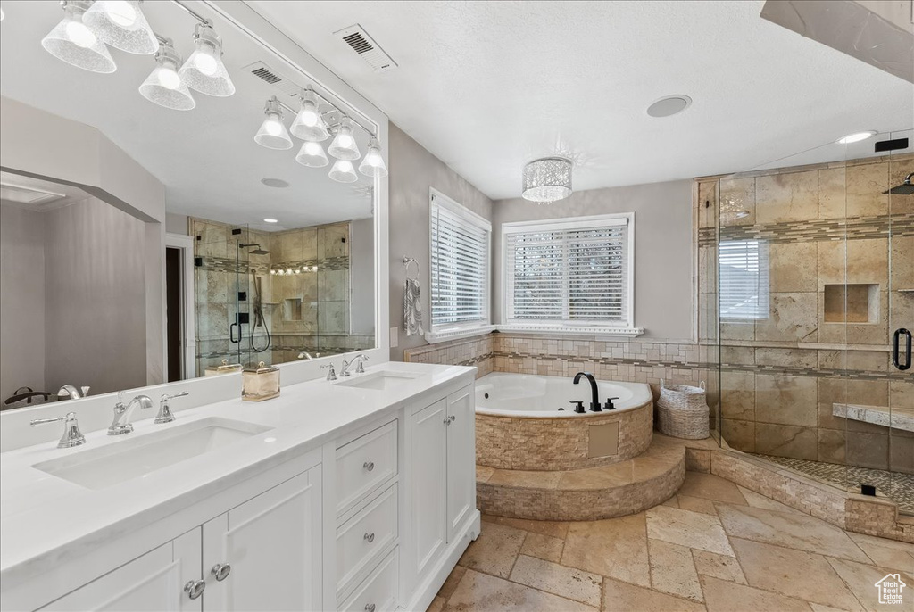 Bathroom with tile flooring, independent shower and bath, oversized vanity, and dual sinks