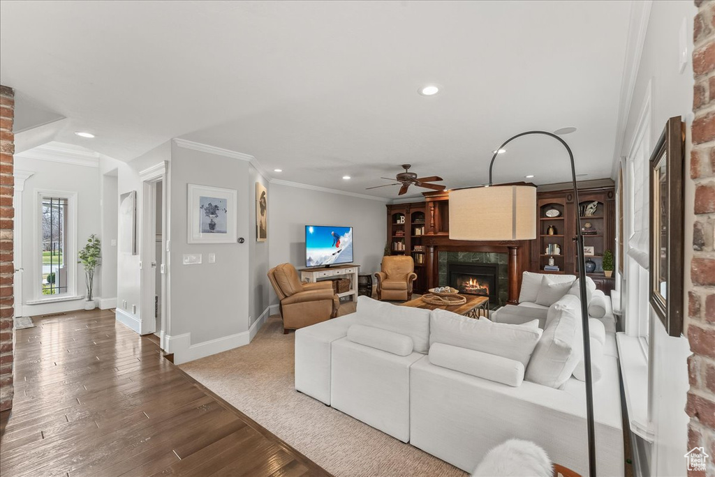 Living room with brick wall, light hardwood / wood-style flooring, crown molding, and ceiling fan