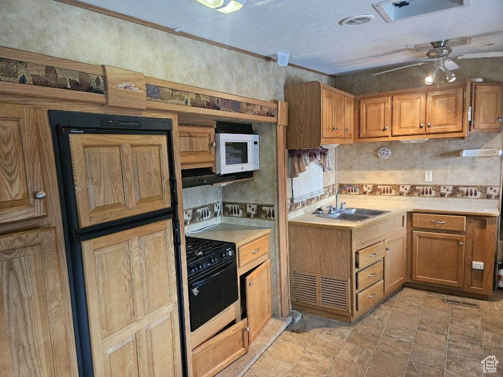 Kitchen with ceiling fan, crown molding, sink, gas stove, and light tile floors