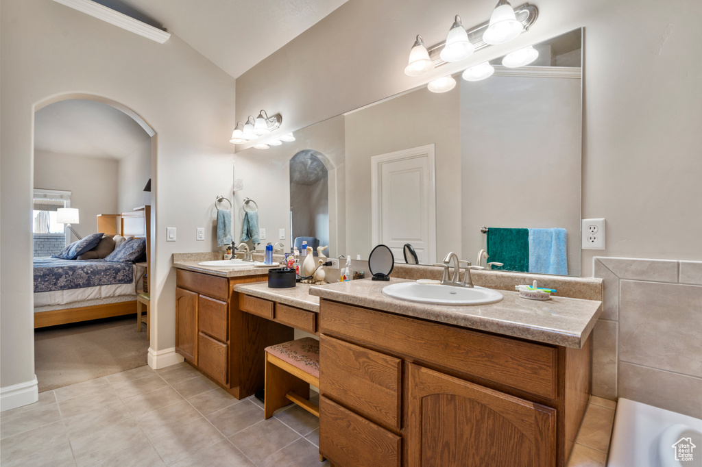 Bathroom with tile flooring, lofted ceiling, and dual vanity