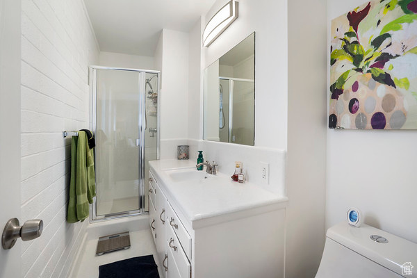 Bathroom with a shower with shower door, large vanity, and toilet