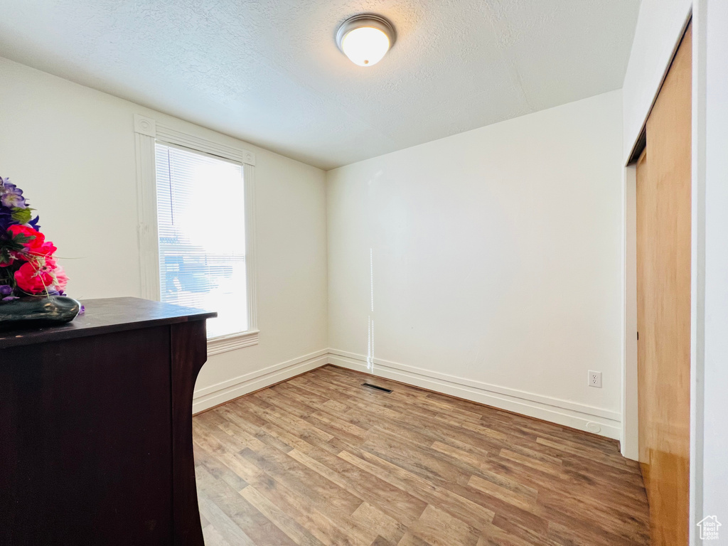 Unfurnished bedroom with a textured ceiling, light hardwood / wood-style flooring, and a closet