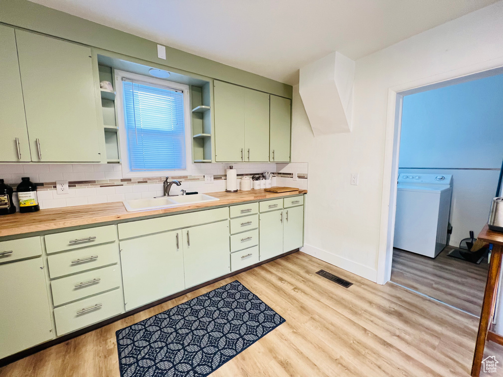 Kitchen featuring green cabinetry, light hardwood / wood-style floors, and washer / dryer