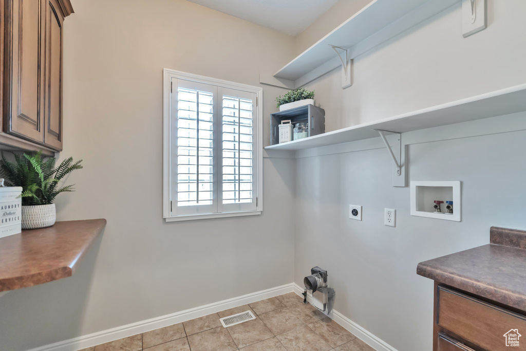 Clothes washing area with light tile flooring, electric dryer hookup, and washer hookup