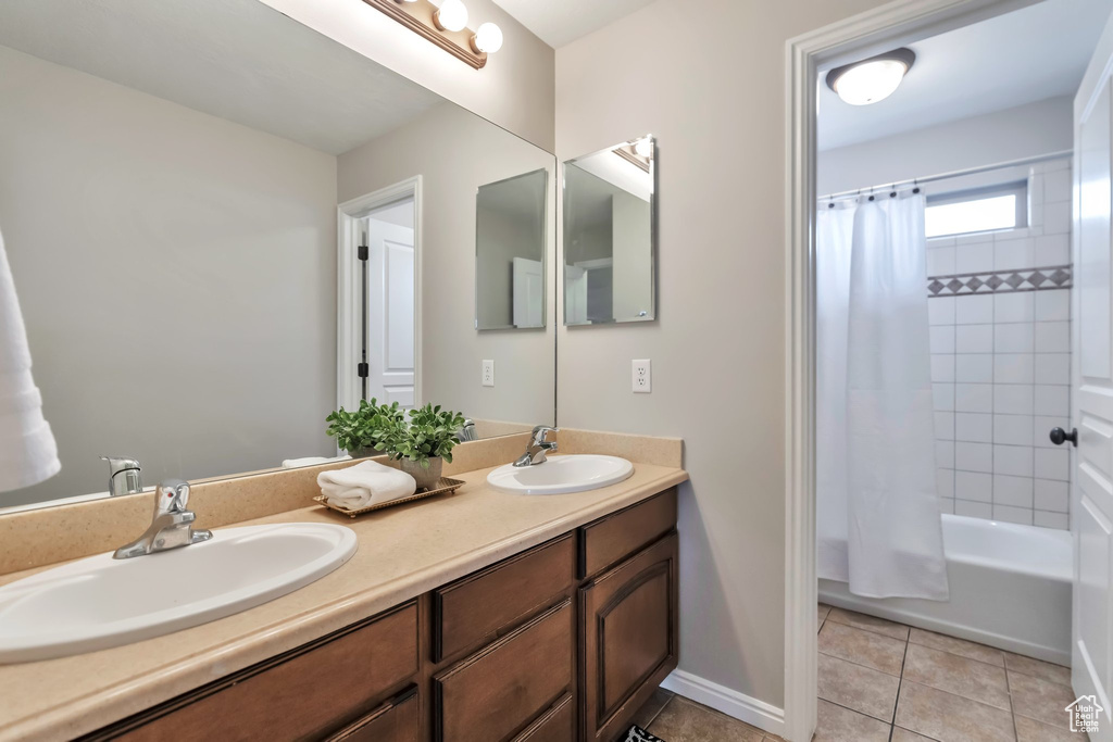 Bathroom featuring shower / tub combo with curtain, double sink, large vanity, and tile floors
