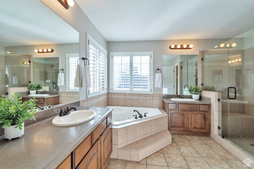 Bathroom featuring separate shower and tub, vanity with extensive cabinet space, and tile floors
