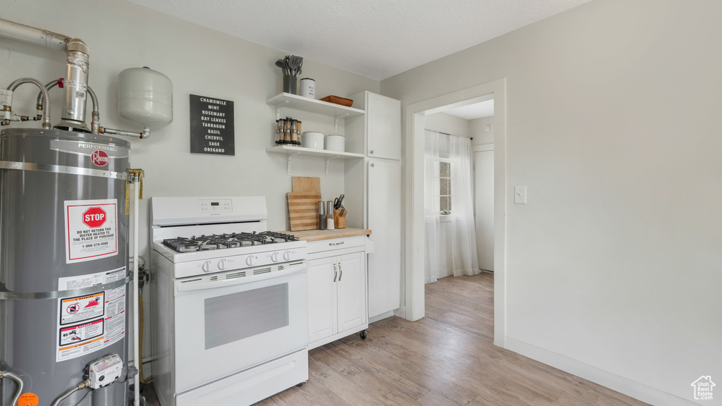 Kitchen with water heater, white cabinetry, gas range gas stove, and light hardwood / wood-style floors