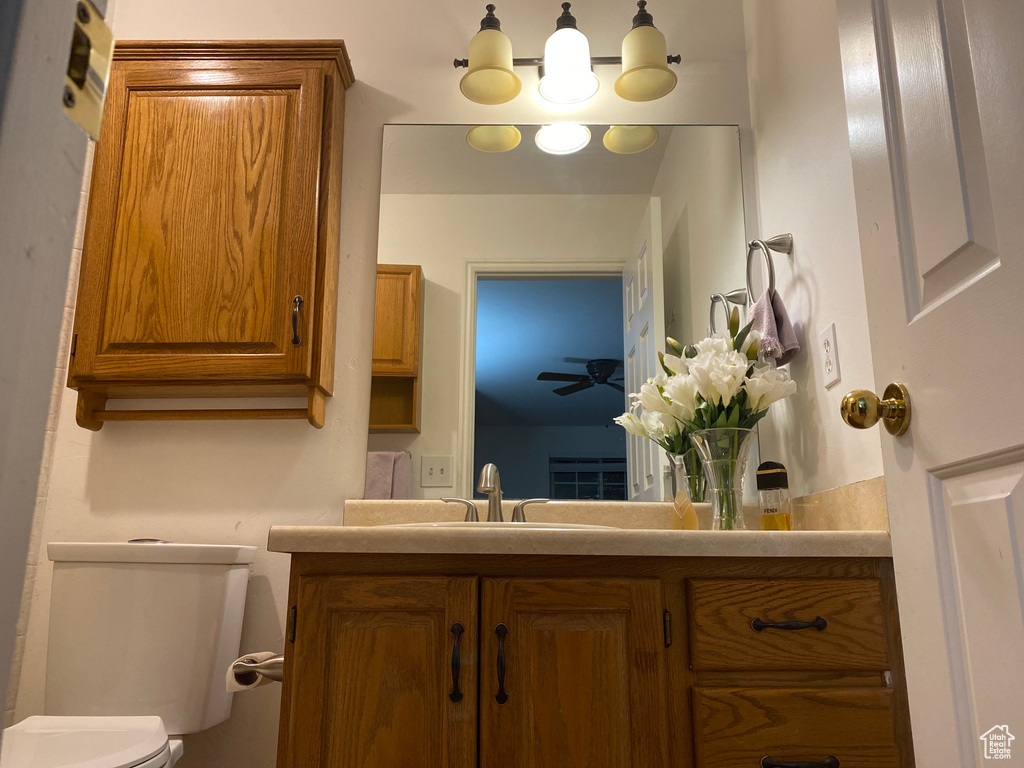 Bathroom featuring toilet, vanity, and ceiling fan