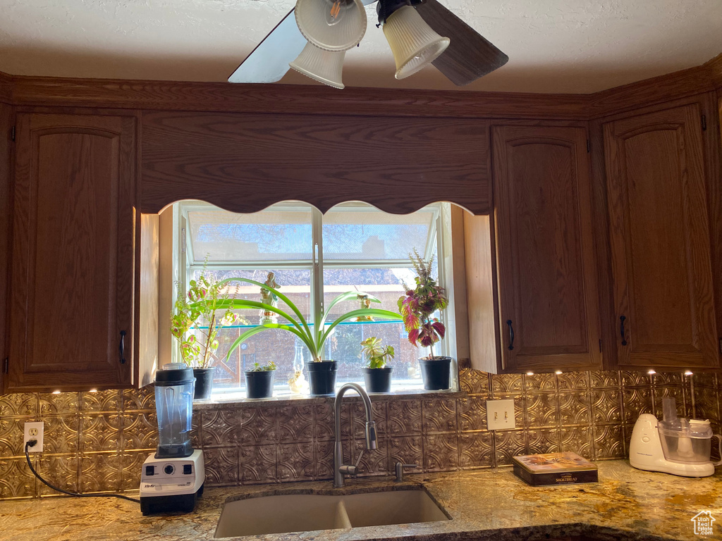Kitchen with backsplash, sink, ceiling fan, and a healthy amount of sunlight