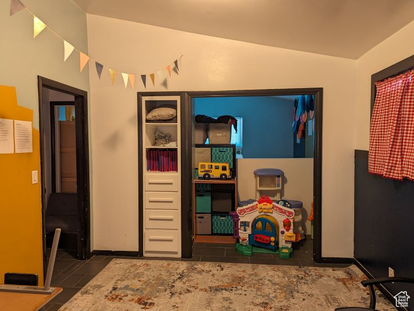 Rec room with dark tile flooring and lofted ceiling