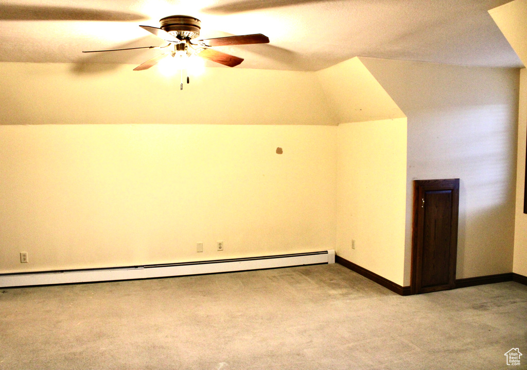 Additional living space with lofted ceiling, baseboard heating, light carpet, and ceiling fan