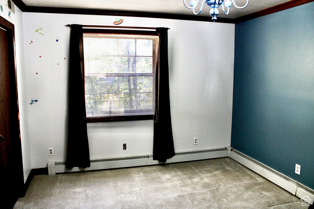 Empty room featuring light colored carpet, ornamental molding, an inviting chandelier, and a baseboard heating unit