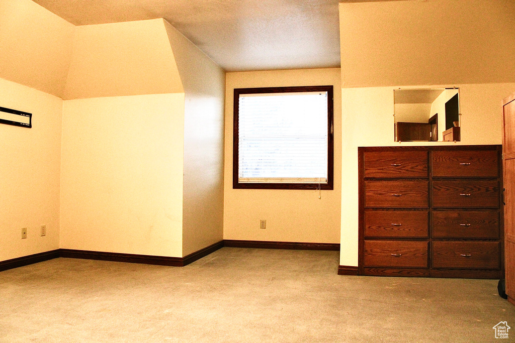 Unfurnished bedroom with lofted ceiling and light carpet