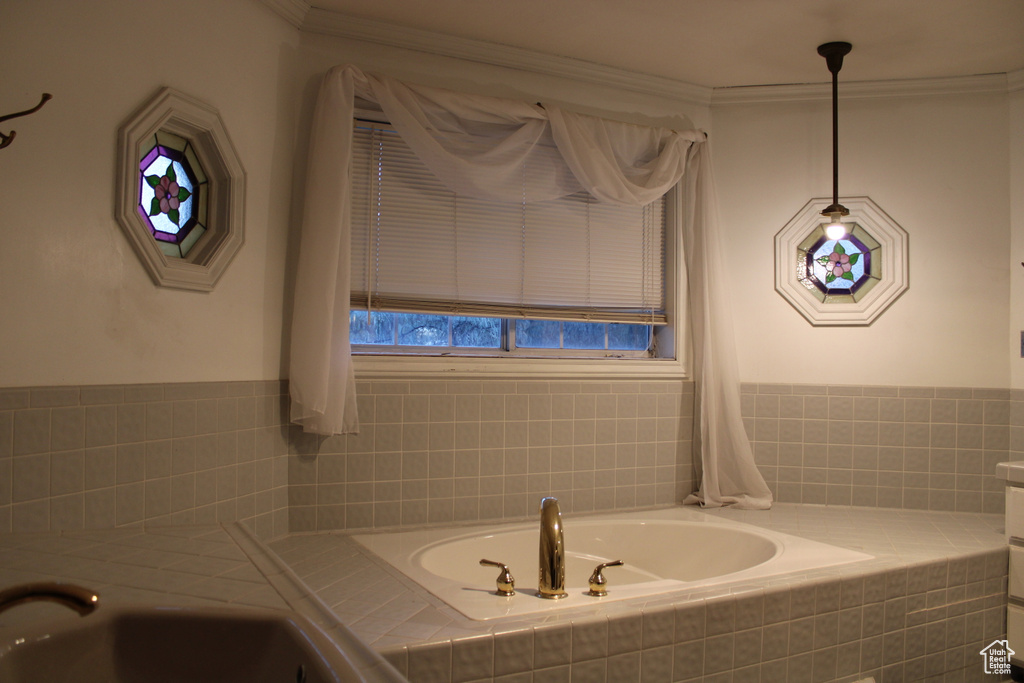 Bathroom featuring a healthy amount of sunlight, a relaxing tiled bath, and crown molding