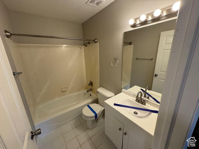 Full bathroom featuring washtub / shower combination, tile floors, a textured ceiling, toilet, and vanity with extensive cabinet space