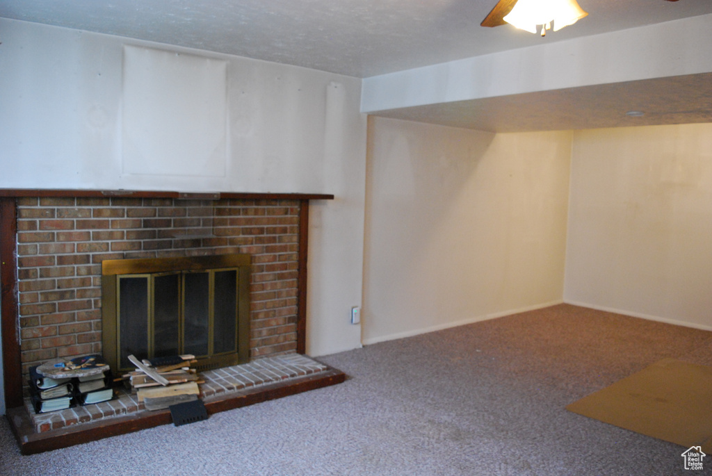 Unfurnished living room with a fireplace, a textured ceiling, carpet floors, and ceiling fan