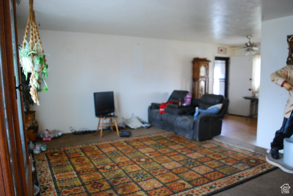Living room with ceiling fan and dark colored carpet