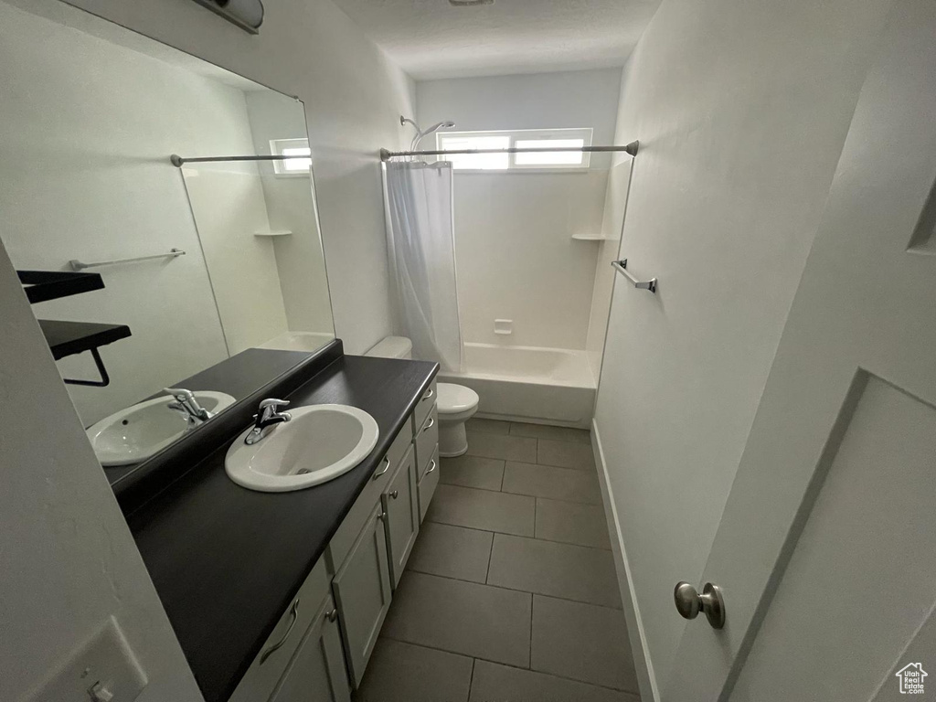 Full bathroom with vanity, toilet, shower / bath combination with curtain, and tile flooring