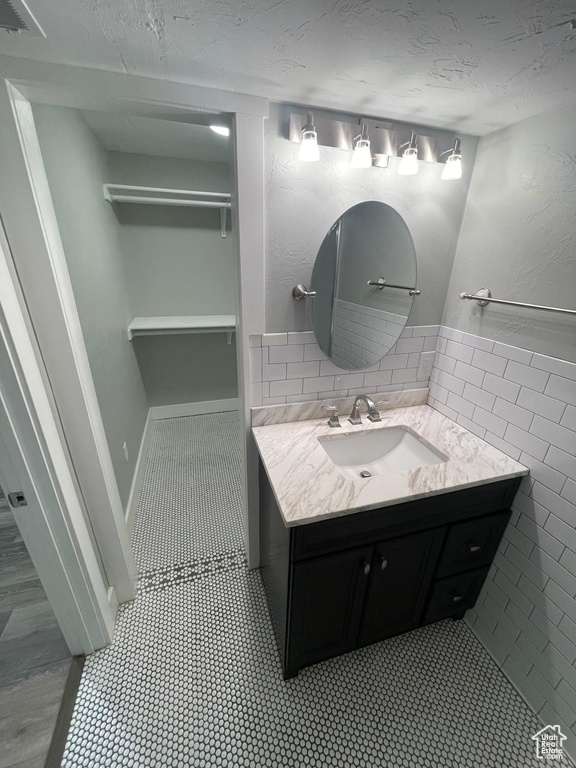 Bathroom featuring tasteful backsplash, oversized vanity, tile walls, and hardwood / wood-style floors