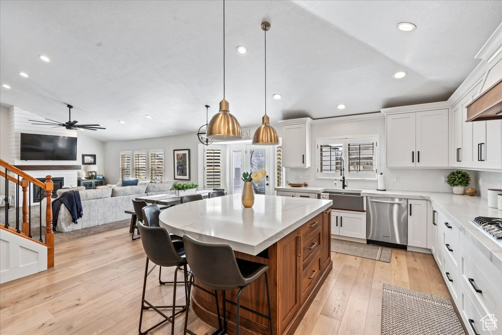 Kitchen featuring ceiling fan, decorative light fixtures, white cabinets, and light hardwood / wood-style flooring
