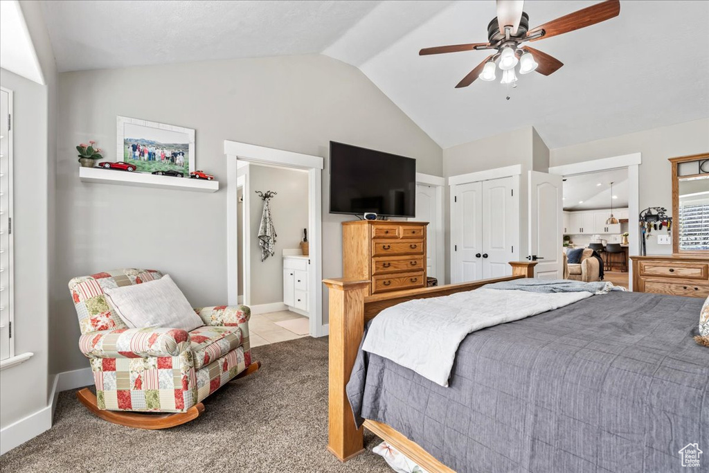 Carpeted bedroom with ensuite bathroom, a closet, lofted ceiling, and ceiling fan