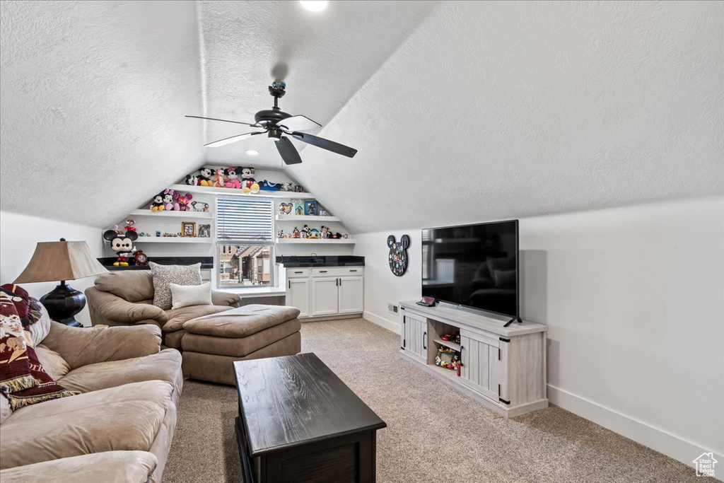 Living room with lofted ceiling, light carpet, a textured ceiling, and ceiling fan