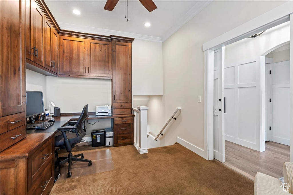 Office with light colored carpet, crown molding, built in desk, and ceiling fan