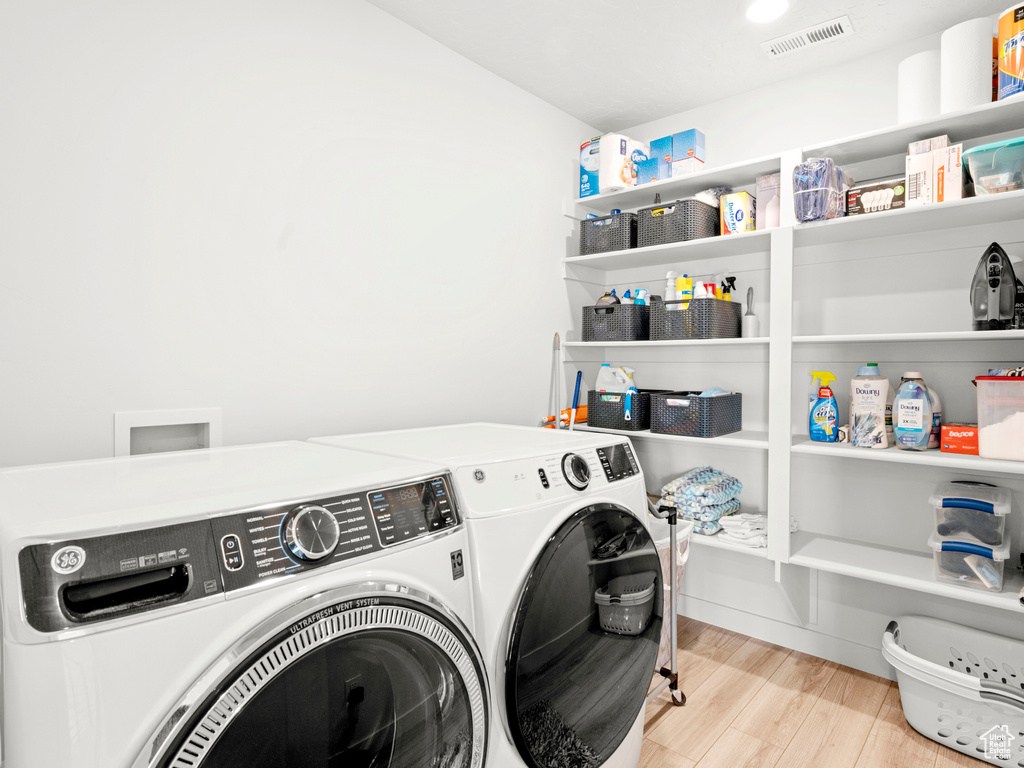 Clothes washing area featuring washer hookup, washer and clothes dryer, and light hardwood / wood-style flooring