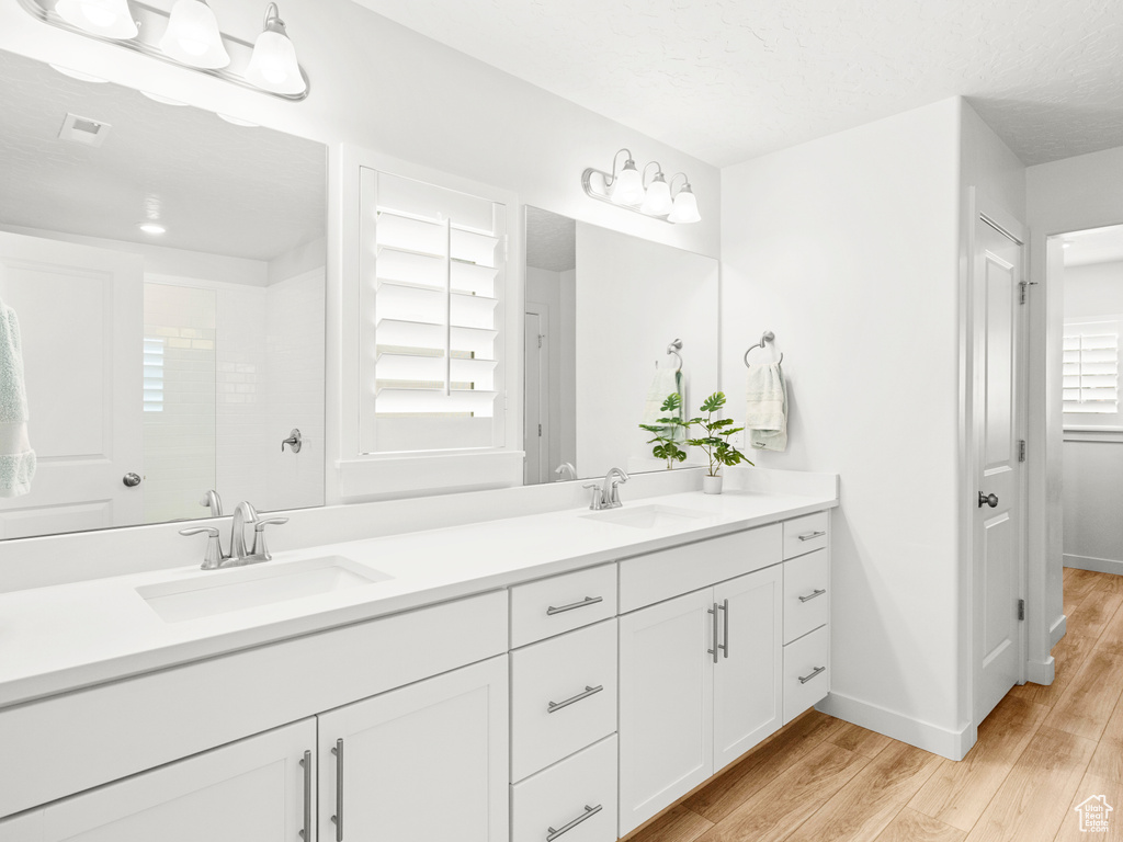 Bathroom with hardwood / wood-style flooring, dual sinks, and large vanity