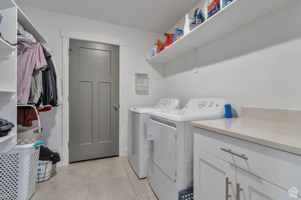 Laundry area featuring light tile floors, washing machine and dryer, and cabinets