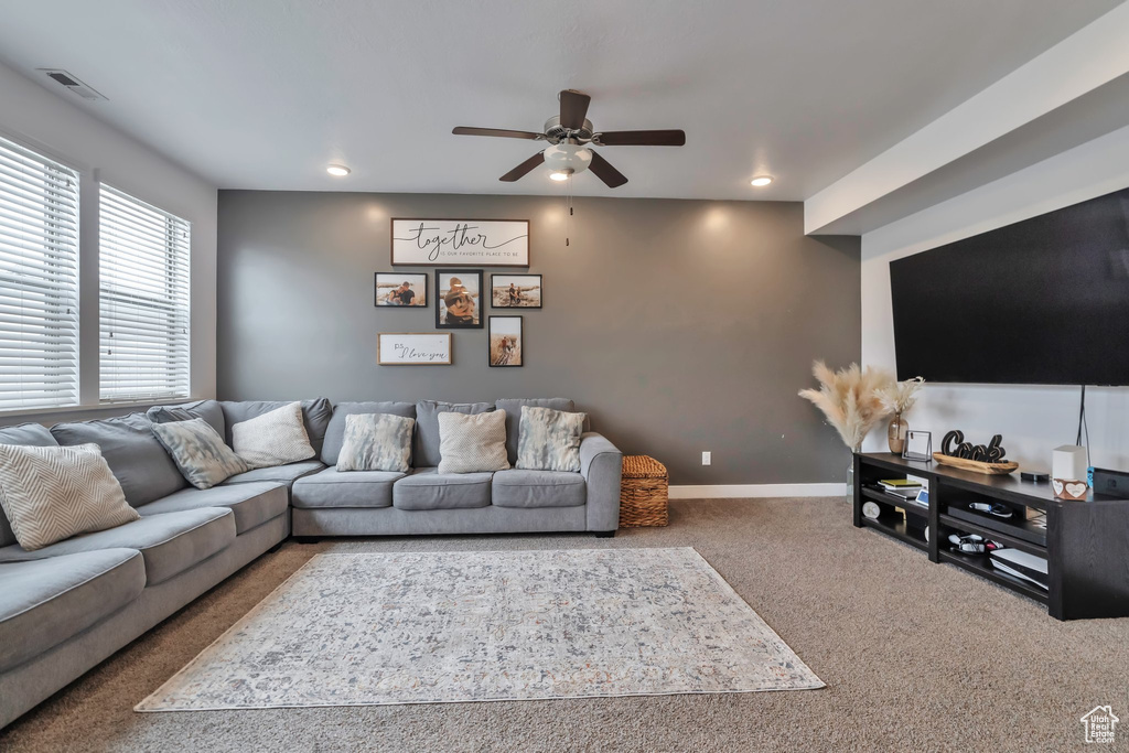 Living room featuring dark colored carpet and ceiling fan