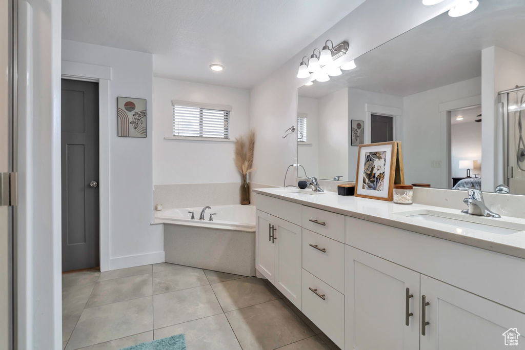 Bathroom with tile flooring, large vanity, dual sinks, and a bathing tub