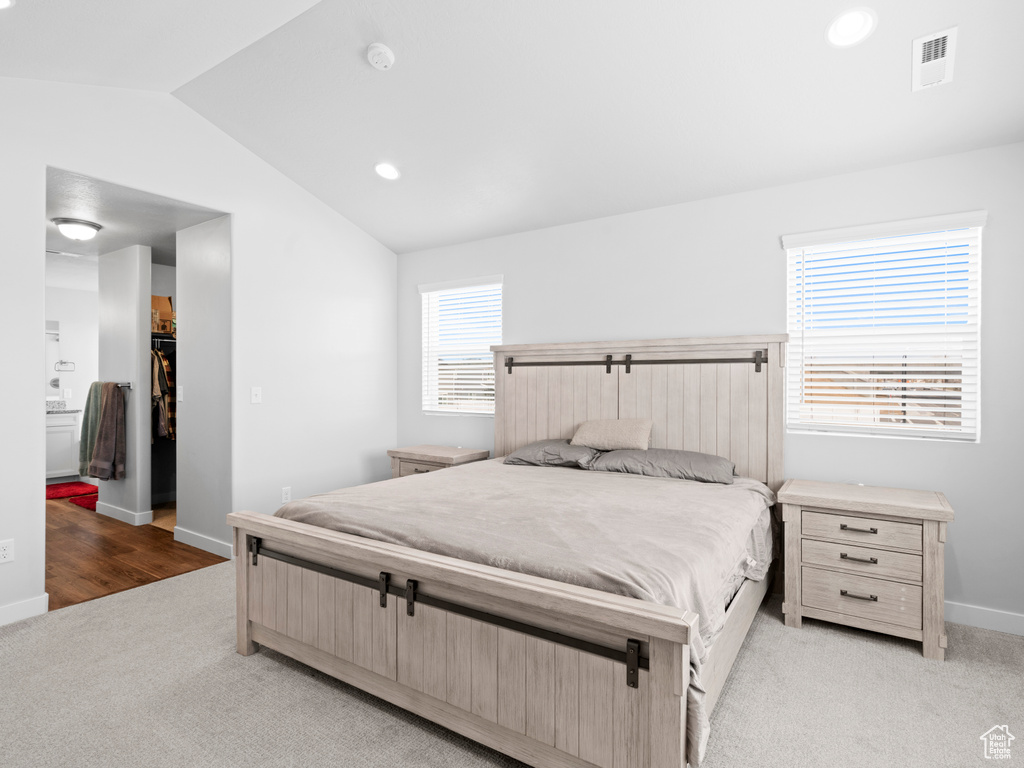 Bedroom with a spacious closet, lofted ceiling, a closet, and light hardwood / wood-style floors