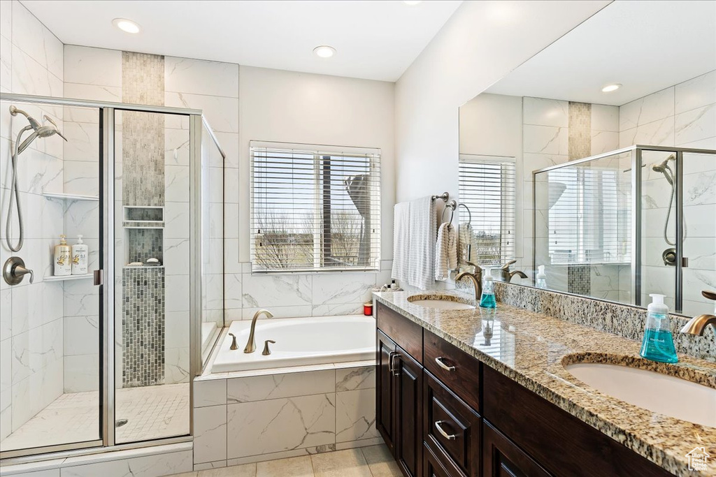 Bathroom with dual sinks, tile flooring, independent shower and bath, and vanity with extensive cabinet space