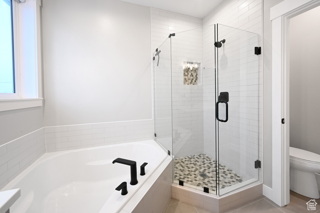 Bathroom featuring shower with separate bathtub, tile floors, and toilet