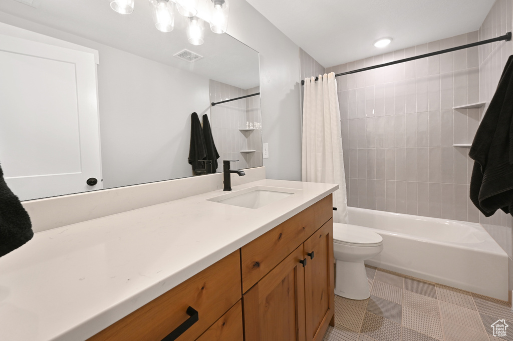Full bathroom with tile flooring, shower / bath combo, large vanity, and toilet