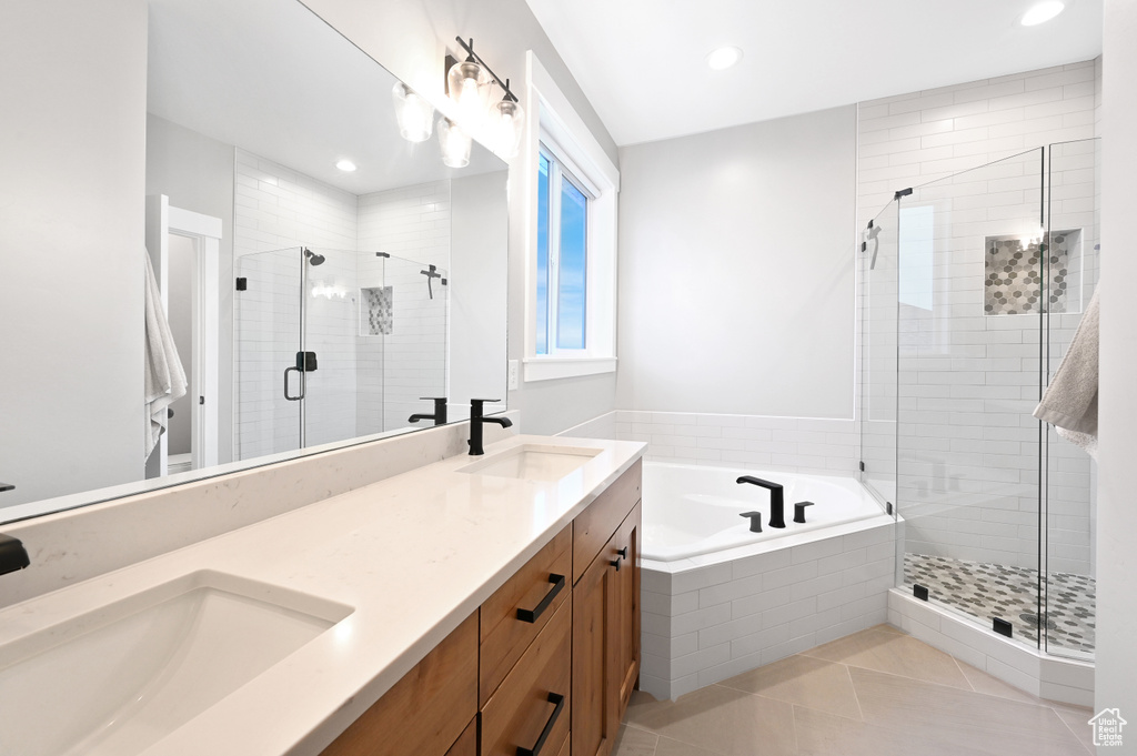 Bathroom featuring shower with separate bathtub, dual sinks, tile flooring, and large vanity