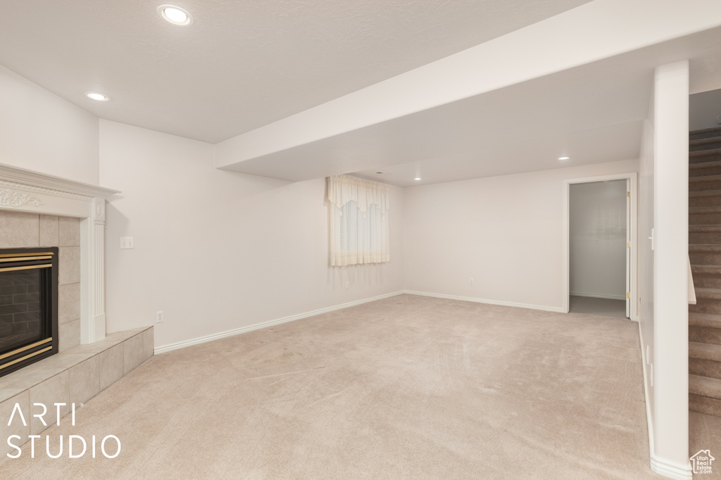 Basement with light colored carpet and a tiled fireplace