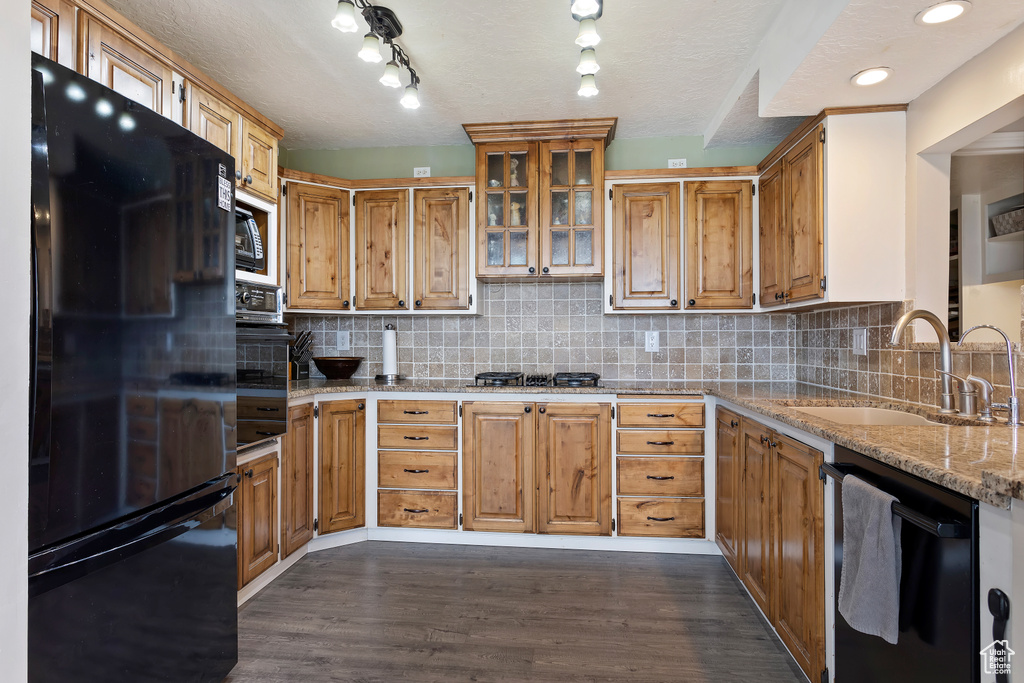 Kitchen featuring backsplash, dark hardwood / wood-style flooring, sink, and black appliances